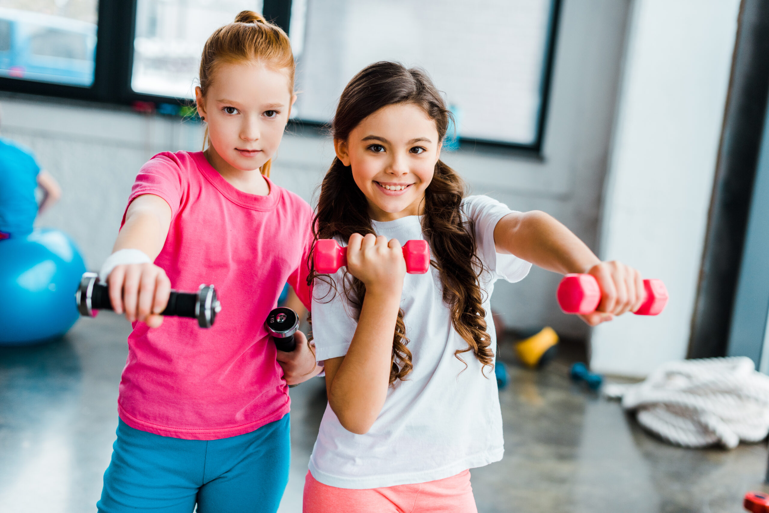 Active kids doing exercise with dumbbells in gym